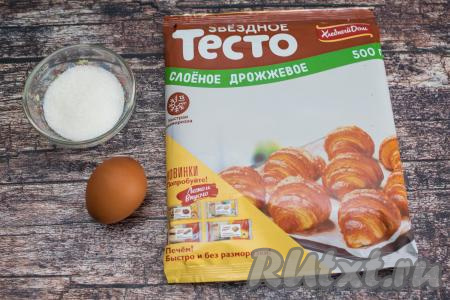 Вот такой скромный набор продуктов нам понадобится для приготовления печенья с сахаром из слоёного дрожжевого теста в духовке. Слоёное дрожжевое тесто достать из морозилки и дать ему разморозиться при комнатной температуре. Я стараюсь заранее перекладывать слоёное тесто из морозилки в холодильник, а непосредственно перед выпечкой достаю его и оно очень быстро размораживается при комнатной температуре. Очень важно не дать дрожжевому слоёному тесту сильно разморозиться, то есть как только оно стало в меру мягким, с ним сразу нужно начинать работать. Если же оно разморозится и после этого полежит при комнатной температуре, оно станет мягким, липким, начнётся процесс его подъёма, с ним будет уже трудно работать.