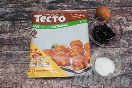 Подготовить продукты для приготовления булочек с вареньем из слоёного дрожжевого теста. Слоёное дрожжевое тесто разморозить до комнатной температуры. В процессе разморозки тесто должно стать достаточно мягким, но не нужно давать ему лежать после размораживания, чтобы оно не начало подниматься ещё до того, как вы начнёте формировать из него булочки. Варенье можно взять любое (у меня - варенье из чёрной смородины).