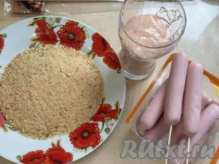 Нанизать каждую сосиску на деревянную шпажку. На плоскую тарелку насыпать панировочные сухари.