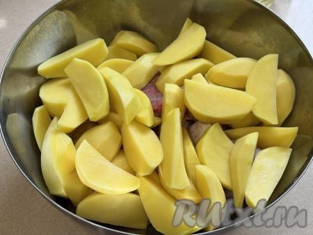 Картошку нарезать на средние дольки. Выложить дольки картофеля и части курицы в глубокую миску.&nbsp;