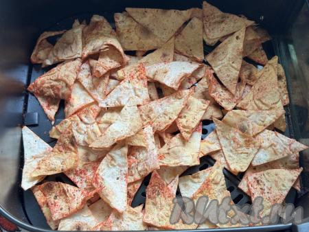 Отправить чашу с кусочками лаваша в аэрогриль, выставить температуру 200 градусов, время - 5 минут. Минуты через 3 с начала запекания чашу с кусочками лаваша нужно достать из аэрогриля, встряхнуть чипсы и отправить их запекаться ещё на 2 минуты.&nbsp;