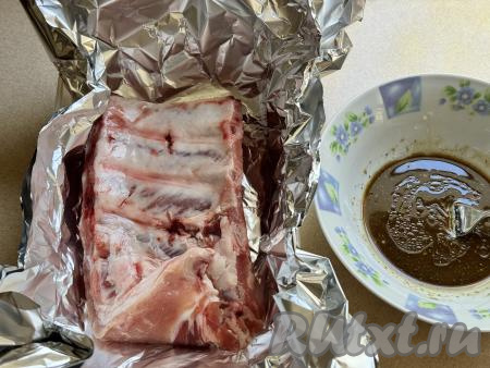 Форму подходящего размера застелить фольгой так, чтобы края фольги были вне краёв формы. В форму, застеленную фольгой, выложить свиные рёбра (разрезать на порционные части я их не стала), равномерно полить их маринадом со всех сторон, накрыть мясо фольгой и поставить в холодильник мариноваться на 2-3 часа (можно оставить и на ночь). В процессе маринования можно 2-3 раза достать рёбра, полить их маринадом, который будет на дне фольги, чтобы они равномерно промариновались со всех сторон. Соль я не добавляла, так как соевый соус достаточно солёный.