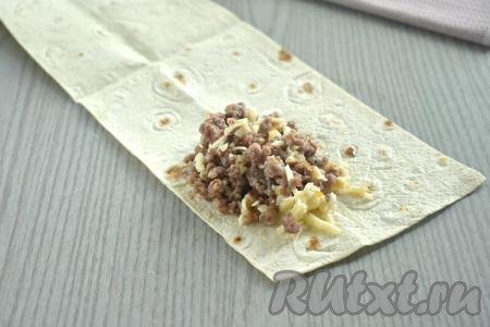 Фарш, смешанный с сыром, зрительно делим на 4 равных части. Ближе к одному из узких краёв полоски из лаваша выкладываем одну часть фарша, смешанного с сыром (это примерно 1 полная с верхом столовая ложка).
