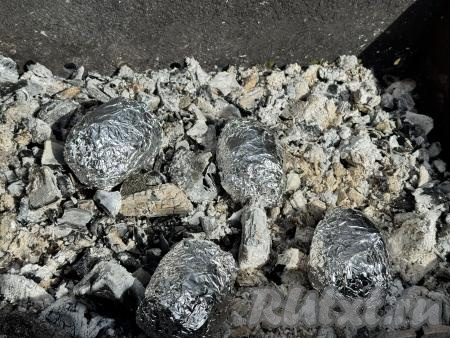 В мангале заранее подготовить угли, они должны быть "седыми", хорошо раскалёнными, но прямого огня быть не должно. Выложить картошку в горячие угли мангала. Закопать картошку в угли, чтобы она готовилась исключительно под углями.