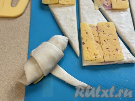 Слегка растягивая короткую сторону треугольника и начиная с этой стороны (то есть со стороны с начинкой), свернуть тесто с начинкой в рулет.