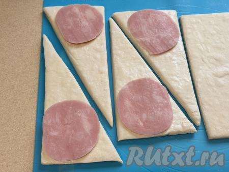 Ближе к короткой стороне каждого треугольника выложить тонкий кусочек ветчины.