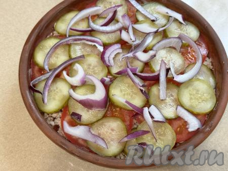Лук нарезать на тонкие полукольца и выложить поверх огурца.
