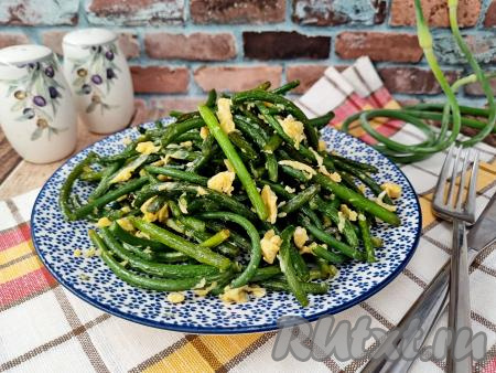 Аппетитные, вкусные, сочные чесночные стрелки, жареные с яйцом, переложить со сковороды на тарелку и в горячем виде в качестве закуски или в качестве гарнира подать к столу.
