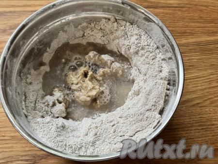 Влить холодную воду. Перемешивать ржаное тесто сначала столовой ложкой. После того как тесто для пельменей станет тяжело перемешивать ложкой, начать замешивать его руками.