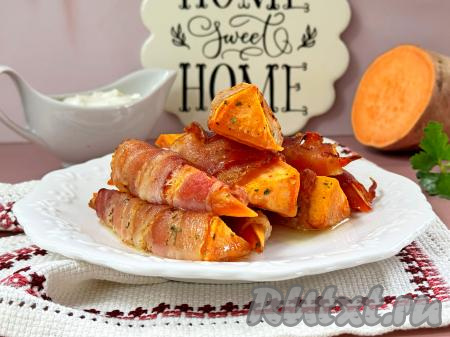 Готовое блюдо достать из духовки. Аппетитный, очень вкусный батат, запечённый в беконе, подать к столу тёплым в качестве закуски или гарнира.