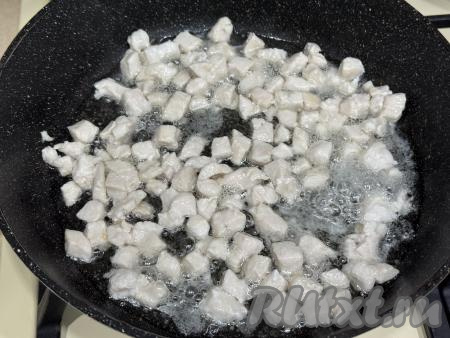 В сковороду влить растительное масло, разогреть, выложить куриное мясо. Обжарить мясо курицы в течение 5 минут (до изменения цвета филе) на среднем огне, периодически перемешивая.