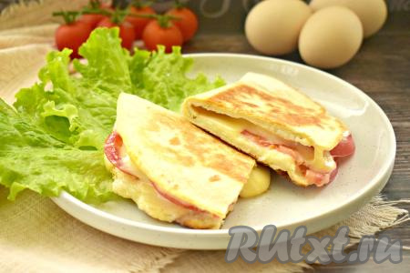 Тортилью, приготовленную с яйцом, помидорами и сыром, перекладываем со сковороды на тарелку и в горячем виде подаём к столу. Сочетание хрустящей лепёшки, сочных помидоров и приятно тянущегося сыра делает это блюдо и вкусным, и аппетитным, и сытным.