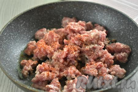 Прежде всего достаём из морозилки покупное слоёное тесто (можно взять как бездрожжевое, так и дрожжевое слоёное тесто, я использовала дрожжевое слоёное тесто) и даём ему разморозиться при комнатной температуре. Пока тесто размораживается, займёмся фаршем. Для этой выпечки можно взять фарш из любого мяса. Фарш можно приготовить в домашних условиях, пропустив кусочки любого мяса (у меня - свинина) через мясорубку. При желании можно использовать и покупной фарш. Разогреваем на сковороде растительное масло, выкладываем фарш.&nbsp;По вкусу солим фарш и приправляем специями (у меня - чёрный молотый перец и паприка).