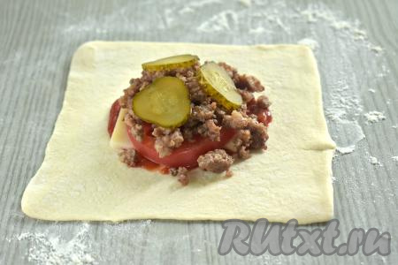 Маринованный огурец нарезаем на достаточно тонкие кружочки. На фарш выкладываем несколько кружочков огурчика.