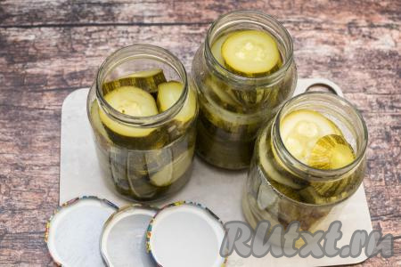 Кабачки, аккуратно утрамбовывая, разложить по банкам. Я на дно банок кладу более крупные кружочки кабачков, самые маленькие кружочки размещаю по бокам банки, плотно укладывая кабачки, но при этом стараясь не деформировать их, чтобы они хорошо держали форму. После того как все кружочки кабачков из кастрюли будут разложены по банкам, сразу накрыть баночки прокипячёнными крышками.