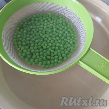 Подготовить широкую посуду (например, миску, кастрюлю, в которую можно поместить сито с горошком), в ней будем бланшировать зелёный горошек. Налить в данную посуду горячую воду, довести во кипения. Небольшое количество горошка (я брала примерно 7 столовых ложек) высыпать в сито. Поместить сито с горошком в миску с кипящей водой так, чтобы горошек был погружён в воду, оставить горошек в кипящей воде (то есть бланшировать его) 30 секунд.