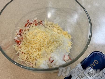 В миску с крабовыми палочками и рисом выложить сыр, натёртый на мелкой тёрке.&nbsp;