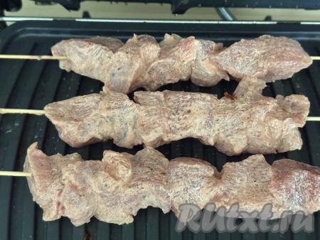 Электрогриль разогреть на режиме "Мясо". Смазать створки электрогриля растительным маслом, выложить шашлык из свинины на шпажках.