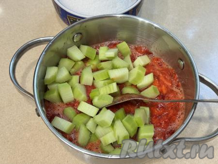 В кастрюлю с размятой клубникой добавить мелкие кусочки ревеня, перемешать столовой ложкой.