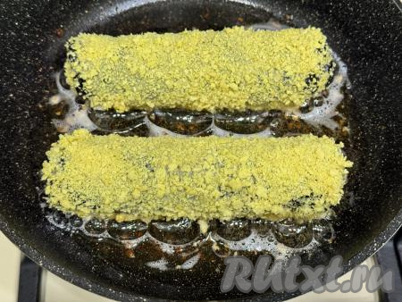В сковороду влить растительное масло, хорошо его разогреть. Выложить заготовки суши хот-догов в сковороду.