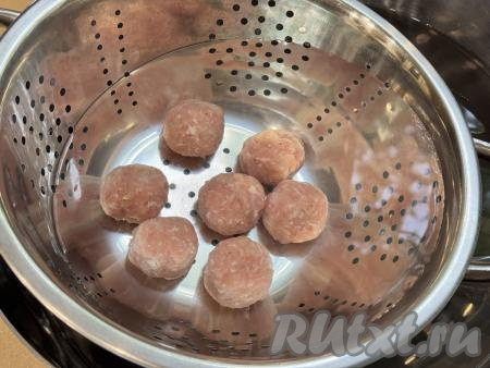 6-7 замороженных мясных шариков выложить в дуршлаг. Опустить дуршлаг с мясными шариками в миску с водой так, чтобы шарики полностью окунулись в воду. Вытащить дуршлаг из воды.
