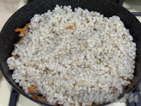 Затем в сковороду с тушёными куриными сердечками выложить промытую варёную перловку.