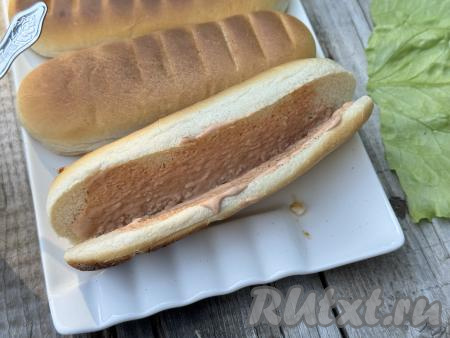 На булочке для хот-дога сделать разрез, не прорезая до конца, чтобы она раскрывалась, как книжка. Разрез булочки смазать подготовленным соусом из кетчупа и майонеза.