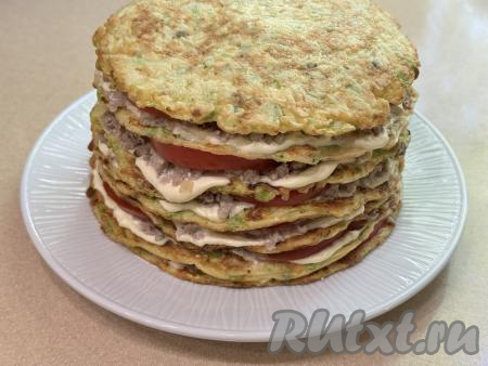 Накрыть следующим кабачковым блином, смазать майонезом с чесноком, частью фарша, выложить насколько кружочков помидора. Таким образом сформировать весь торт. Верхний кабачковый блинчик ничем смазывать не нужно.
