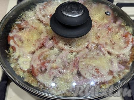 Накрыть сковороду крышкой и готовить пиццу на кабачковой основе минут 5 на медленном огне.