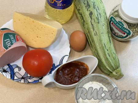 Подготовить продукты для приготовления пиццы на кабачковой основе на сковороде. Колбасу можно взять любую (я взяла варёную). Сыр подойдёт твёрдых или полутвёрдых сортов. Если кабачок с тонкой кожицей, её можно не срезать, мелкие семечки можно не удалять, нужно лишь будет отрезать у кабачка кончики с двух сторон и тщательно его вымыть. Если же у кабачка толстая кожура, её нужно будет срезать, крупные семечки вместе с рыхлой мякотью нужно будет удалить. Для приготовления пиццы нам потребуется 250 грамм подготовленного кабачка. Помидор вымыть.