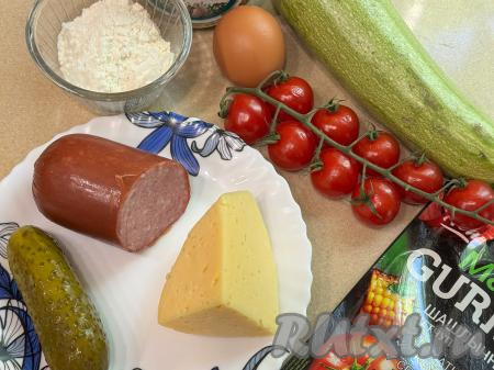 Подготовить продукты для приготовления пиццы из кабачков в аэрогриле. Кабачок я взяла с молодой, то есть с мелкими семечками и тонкой кожицей, поэтому очищать от кожуры его не стала, только отрезала кончики с двух сторон. Если вы будете использовать кабачок с толстой кожурой, тогда её нужно срезать, крупные семечки нужно будет удалить. Для пиццы нам потребуется 340 грамм подготовленного кабачка.  Сыр можно взять любой твёрдых или полутвёрдых сортов. Колбаса подойдёт варёная или полукопчёная. Помидоры вымыть.