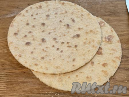 Готовый корж переложить со сковороды на тарелку. Постепенно пожарить творожные коржи из всех раскатанных частей теста. Готовым коржам дать остыть. Обрезать (подравнять) края остывших коржей, приложив сверху тарелку чуть меньшего диаметра (я взяла тарелку диаметром 22 сантиметра). Обрезанные остатки отложить, они нам понадобятся для украшения торта.