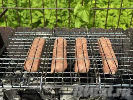 Разместить решётку с купатами на мангале с подготовленными углями.