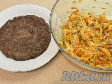 Перемешать овощную начинку из кабачка, моркови и лук. Теперь можно приступать к формированию печёного торта. Для этого на плоскую тарелку нужно выложить первый печёночный блин, смазать его частью начинки, сверху выложить следующий блин, смазать его частью начинки.