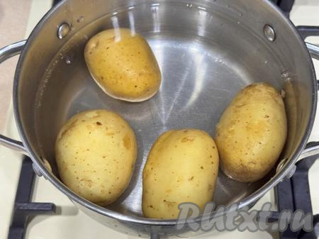 Молодой картофель будем готовить, не очищая от кожуры, поэтому его нужно тщательно вымыть, потереть кожуру железной щёткой для мытья посуды, убирая с поверхности картошки все загрязнения. Подготовленные картошины выложить в кастрюлю, залить полностью водой и поставить на сильный огонь.