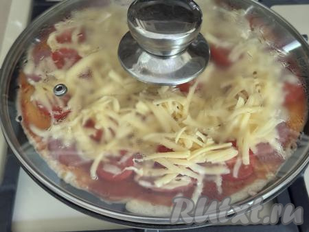 Накрыть сковороду крышкой и готовить ленивую пиццу на минимальном огне минут 5 (до полного расплавления сыра).