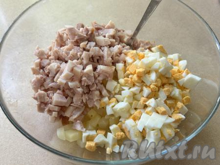 В миску с ананасами добавить мелко нарезанное копчёное мясо курицы и яйца, нарезанные на мелкие кубики.
