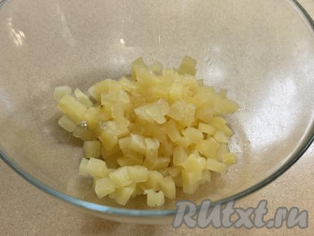 Консервированные ананасы достать из сиропа, в котором они находятся в банке, затем можно выложить на бумажные полотенца, чтобы убрать лишнюю жидкость. Нарезать ананасы на мелкие кубики, выложить в миску.