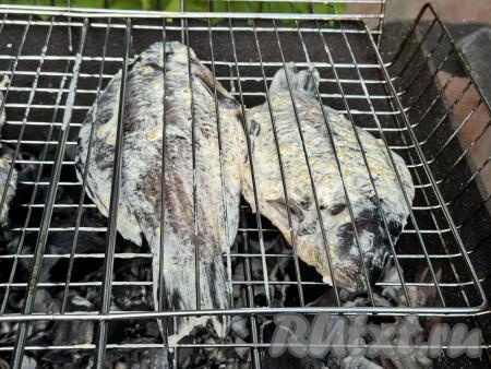 Выложить решётку с карасями на мангал с раскалёнными углями.