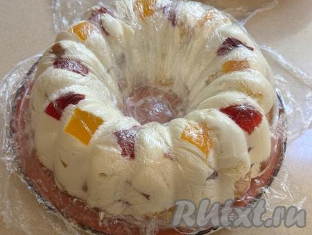 Накрыть торт сверху концами плёнки, свисающими с краёв формы, и убрать в холодильник до полного застывания (минимум часа на 4, можно на ночь). Готовый торт&nbsp;"Битое стекло" с бисквитом и желе освободить от плёнки, накрывающей его сверху. Перевернуть форму с тортом на плоскую тарелку, снять форму и аккуратно отделить десерт от плёнки.