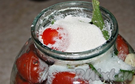 Заполнить банку помидорами, все время встряхивая, чтобы поместилось больше помидор и они разместились плотнее. И прямо в банку насыпать соль и сахар.