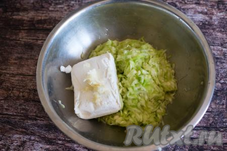 В миску с кабачковой массой, отжатой от сока, добавить творог и очищенные зубчики чеснока, натёртые на мелкой тёрке.