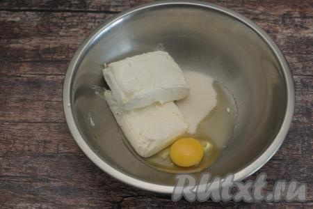 В глубокую миску выложить творог, вбить сырое яйцо, сразу же всыпать сахар.
