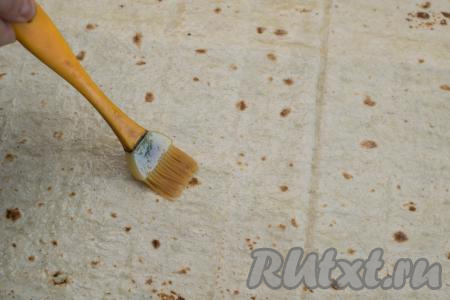 У меня были два прямоугольных лаваша, каждый из которых был размером 31 сантиметр на 50 сантиметров. На рабочую поверхность выложить первый лист лаваша, немного внахлёст выложить второй лист лаваша, в результате из двух листов лаваша получится один большой лист из лаваша. Получившийся большой лист из лаваша при помощи кулинарной кисточки смазать яичным белком.