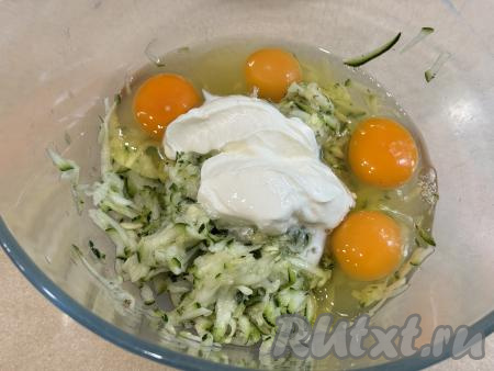 В миску с кабачковой массой добавить сырые яйца и сметану.