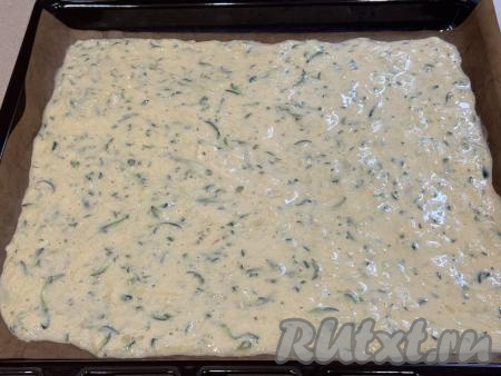 Противень застелить пергаментом, выложить кабачковое тесто, распределив его ровным слоем. Я взяла квадратный противень с размером стороны 30 сантиметров. Если не уверены в качестве пергамента, тогда перед выкладыванием кабачкового теста немного смажьте бумагу маслом, чтобы готовый корж хорошо отделялся от пергамента.