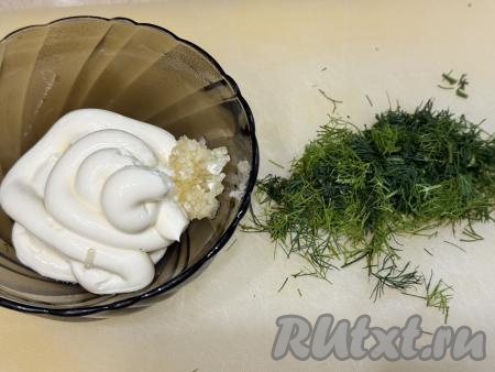 Пока кабачковый корж остывает, можно заняться начинкой для рулета. Для этого в миске нужно соединить майонез, мелко нарезанную зелень и пропущенный через пресс чеснок, перемешать.