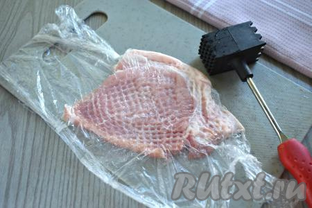 Каждый пласт свинины кладём на разделочную доску и отбиваем кулинарным молотком с двух сторон до получения отбивной толщиной 0,7-1 сантиметр. Чтобы в процессе отбивания свинины кусочки мяса не разлетались по кухне, можно перед отбиванием накрыть мясо пищевой плёнкой и отбивать мясо через плёнку.