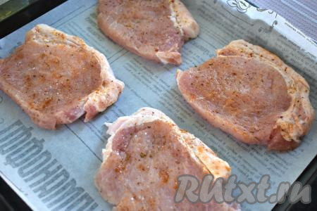 Заготовки отбивных из свинины перекладываем на противень, предварительно застеленный пергаментом (или фольгой).