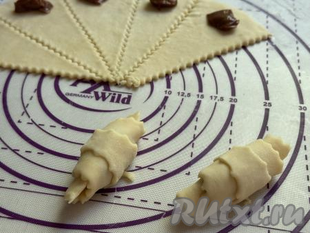 Начиная со стороны с начинкой из варёной сгущёнки, свернуть каждый треугольник из песочного теста в рулетик, у нас получится рогалик, как на фото. Постепенно сформировать все 24 рогалика со сгущёнкой.&nbsp;